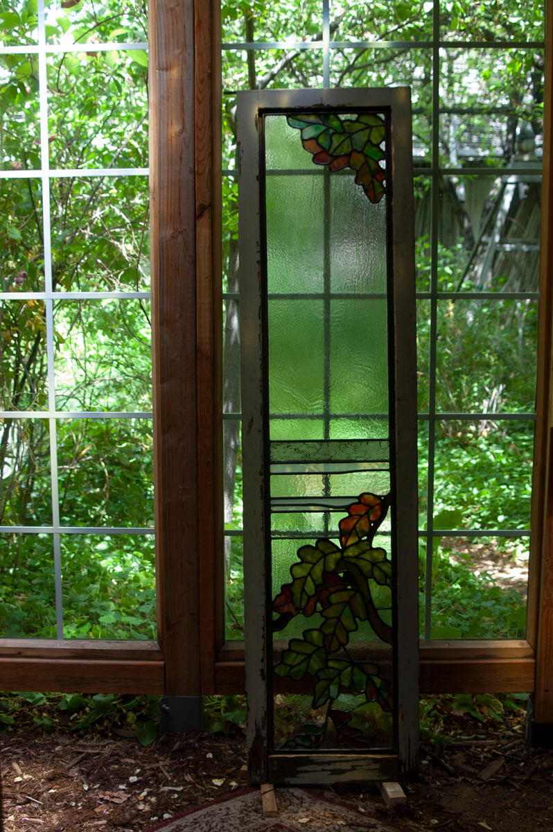 The refurbished window is returned to its wooden frame, where it is temporarily secured before being...